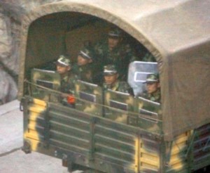 Chinese soldiers with riot shields sit in the back of an army truck as they pass through the city of Kangding, located around 400 kilometres (250 miles) west of Chengdu in Sichuan Province